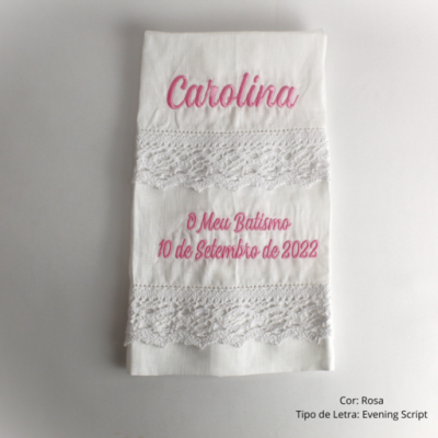 Toalha branca bordada com renda e texto em rosa 'Carolina' e 'O Meu Batismo 10 de Setembro de 2022'