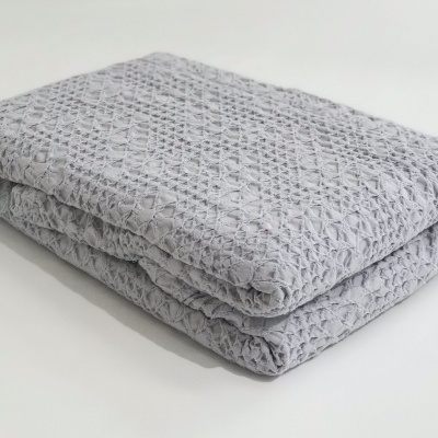 Cobertor ou manta cinzento com padrão geométrico dobrado