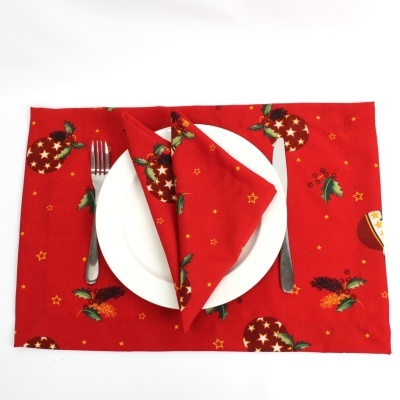 Jogo americano e guardanapo vermelho com motivos natalícios, prato branco e talheres