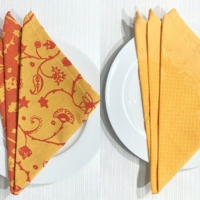 Dois pratos brancos com guardanapos de tecido coloridos e dobrados.