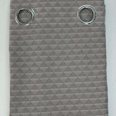 Cortina cinzenta com padrão triangular e ilhós metálicos.