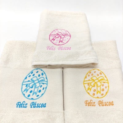 Toalhas brancas bordadas com ovos de Páscoa rosa, azul e amarelo e texto Feliz Páscoa
