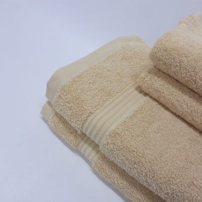 Toalhas de banho bege dobradas sobre fundo branco