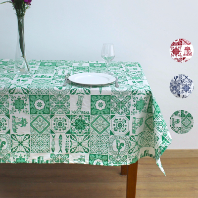 Toalha de mesa verde e branca com padrão de azulejos, prato branco, copo de vidro e vaso com flores