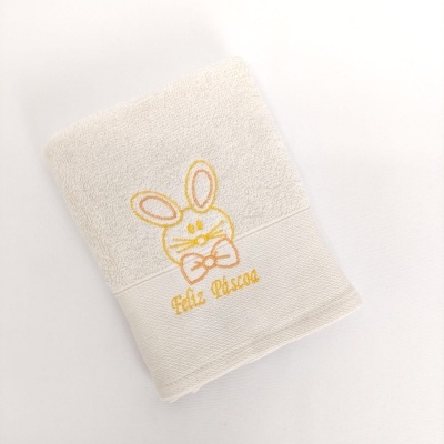 Toalha branca com bordado de coelho e texto Feliz Páscoa em amarelo