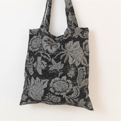 Saco de tecido reutilizável com estampa floral cinza e preto pendurado na parede