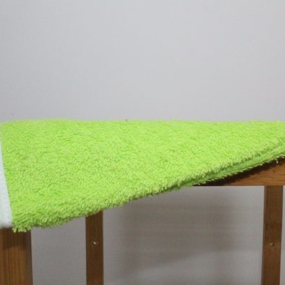 Toalha verde de microfibra sobre móvel de madeira