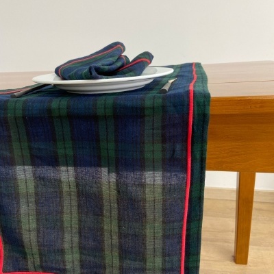 Toalha de mesa e guardanapo xadrez verde azul com risca vermelha sobre mesa de madeira clara