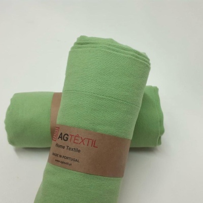 Duas toalhas verdes enroladas com etiqueta AG TÊXTIL sobre fundo branco