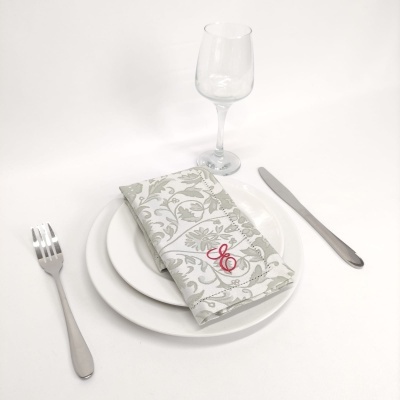 Mesa posta com prato branco, talheres, copo e guardanapo bordado