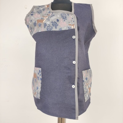 Colete cinza escuro com padrão floral azul e bege em bolsos e parte superior, com botões brancos na frente.