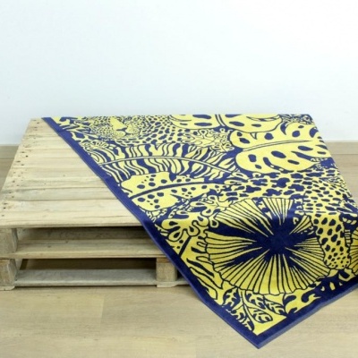 Manta amarela e azul escuro com padrão floral sobre palete de madeira