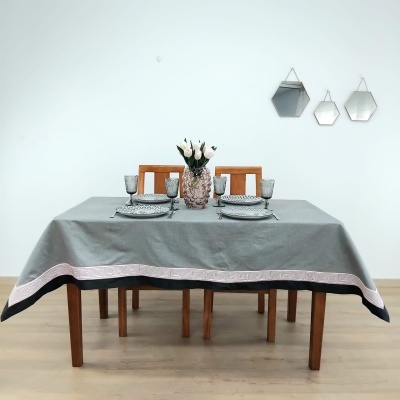Mesa de madeira com toalha cinzenta, pratos, copos, vaso com flores e espelhos hexagonais na parede