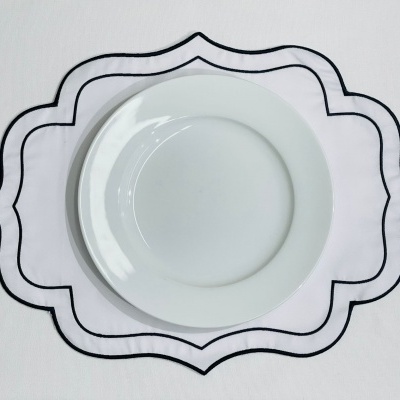 Prato branco redondo sobre toalha branca com padrão preto