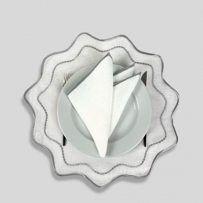 Prato branco com guardanapo branco dobrado e talheres sobre toalha ondulada cinzenta