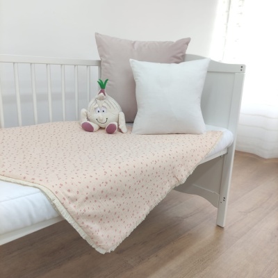 Cama de criança com cobertor creme floral, almofadas branca e bege e brinquedo de pelúcia alho