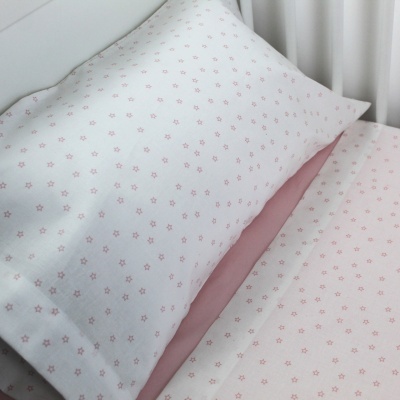 Almofada e lençol brancos com pequenas estrelas cor de rosa