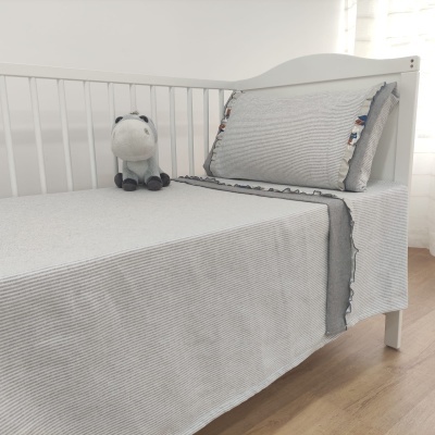 cama de bebé com roupa de cama cinzenta e almofada decorativa e peluche
