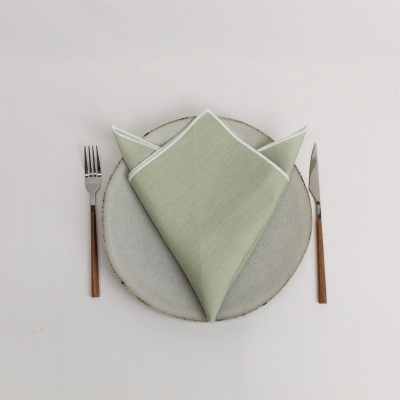 Conjunto de jantar com prato cinzento, guardanapo verde claro e talheres com cabo em madeira