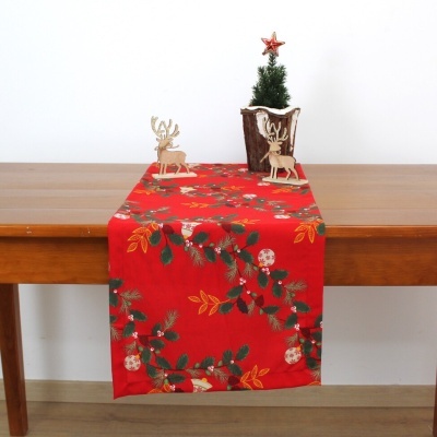 Mesa com caminho de mesa vermelho festivo, renas de madeira e mini árvore de Natal decorativa