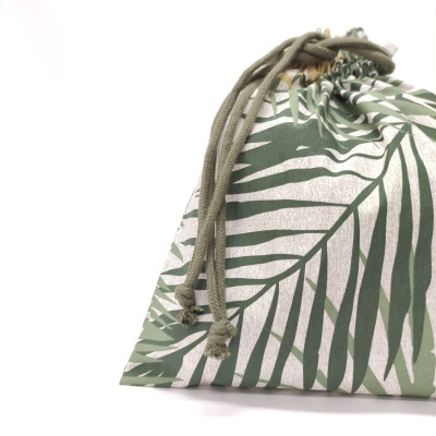 Saco de tecido com padrão de folhas verdes e cordões de fecho verdes