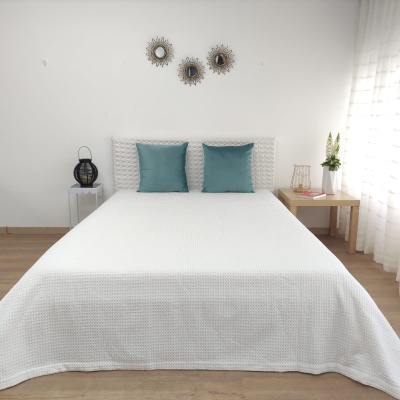 Cama de casal com cobertura branca e duas almofadas azuis