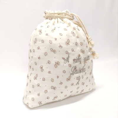 Saco de tecido branco com padrão de flores castanhas e texto bordado