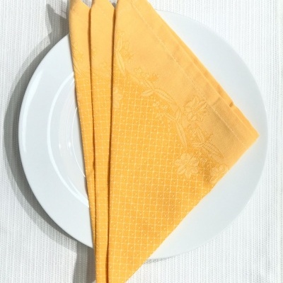 Guardanapo amarelo dobrado em cima de prato branco