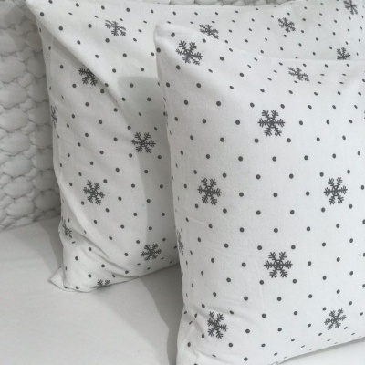 Almofadas brancas com padrão de flocos de neve negras numa cama
