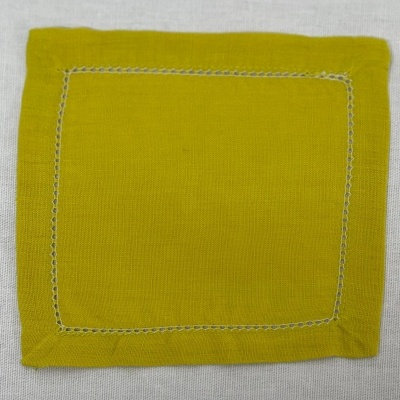 Guardanapo verde-amarelo quadrado com bordado branco em fundo cinzento