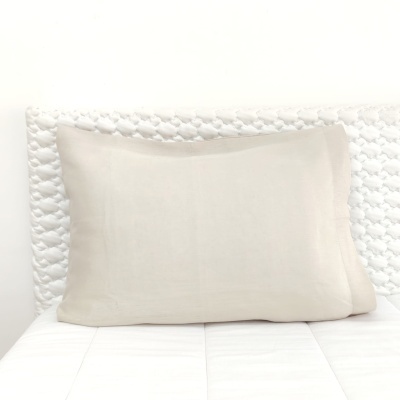 Travesseiro bege claro sobre colchão branco com cabeceira acolchoada branca