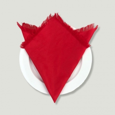 Guardanapo vermelho de tecido com bordas desfiadas sobre prato branco