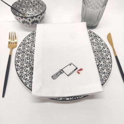 Conjunto de jantar com padrão preto e branco, talheres dourados e guardanapo bordado