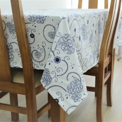 Toalha de mesa branca com padrão azul e cadeiras de madeira