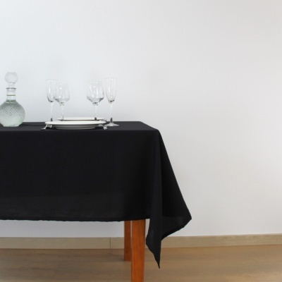 Mesa com toalha preta, copos e garrafa de vidro transparente