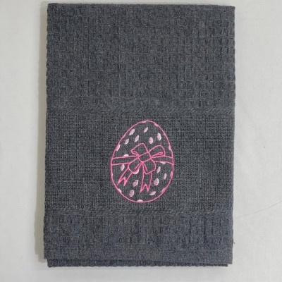 Toalha cinzenta com bordado de ovo rosa com laço.