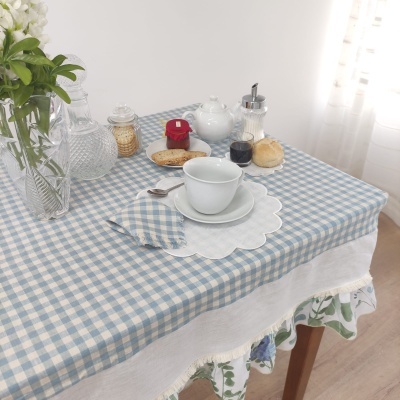 toalha de mesa xadrez azul e branco com louça e decoração sobre mesa de madeira