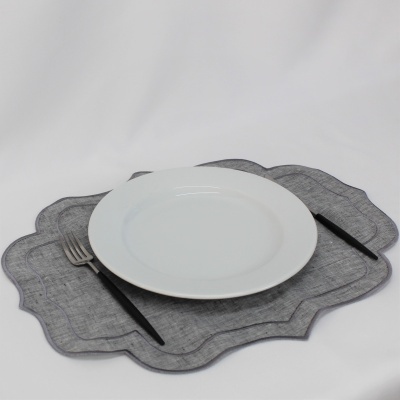 Prato branco redondo sobre suporte de mesa cinzento com garfo e faca