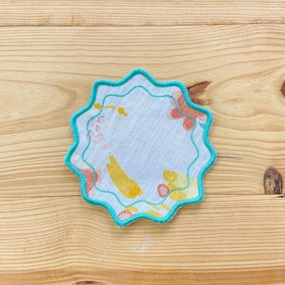 Lenço quadrado colorido com bordado azul sobre superfície de madeira clara