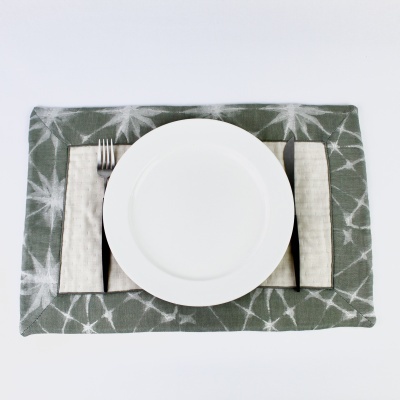 Prato branco num conjunto de mesa com guardanapo bege e suporte verde com padrão branco