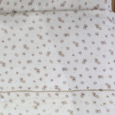 Cobertor estofado creme com pequenas flores castanhas claro e botão branco