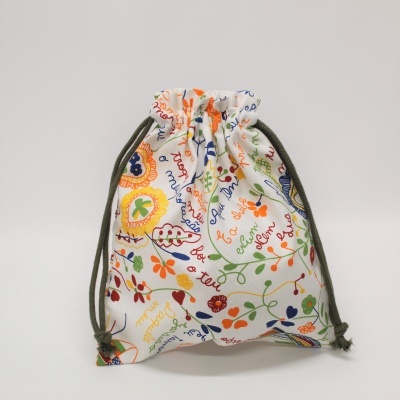 Saco de pano branco com padrão floral colorido e cordões verdes