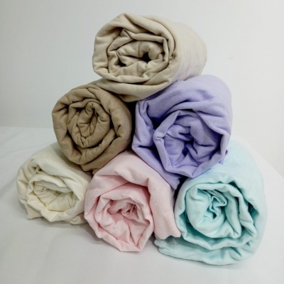 Seis mantas enroladas em várias cores sobre superfície branca