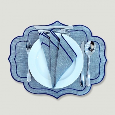 Conjunto de mesa com guardanapo cinzento e bordas azuis, prato branco e talheres prateados