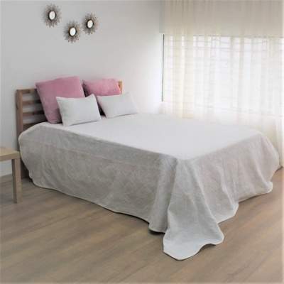 Cama de casal com lençol cinza, almofadas brancas e cor-de-rosa, cabeceira em madeira e espelhos na parede