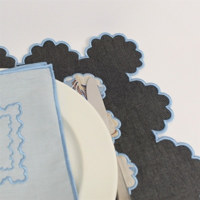 Guardanapo azul com bordado e placemats escuros com padrão floral e contorno azul