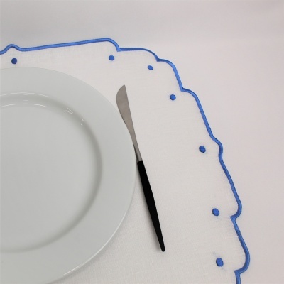guardanapo branco com borda azul e pontos azuis sob prato branco e faca com cabo preto