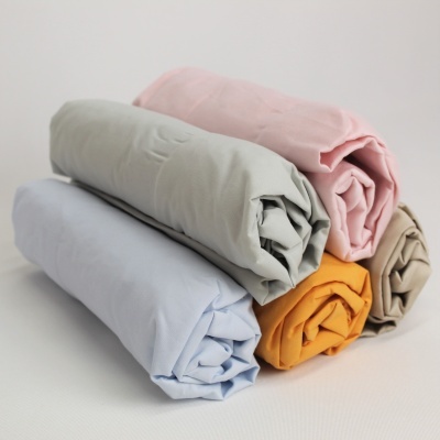 Cinco tecidos enrolados de várias cores empilhados sobre uma superfície branca