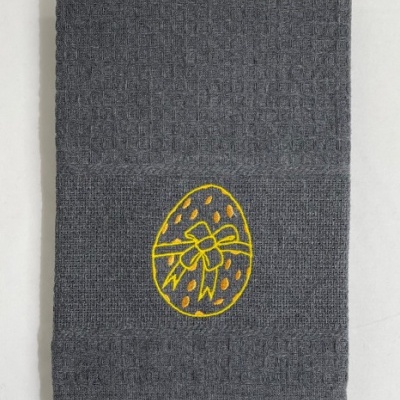 Toalha cinzenta com bordado amarelo de ovo decorativo.