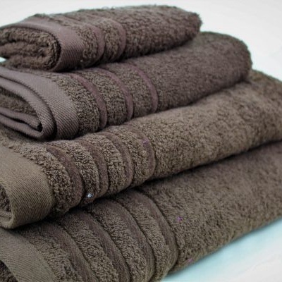 Conjunto de quatro toalhas castanhas dobradas sobre superfície branca